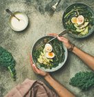 Quinoa, kale, beans, avocado, egg with creamy tahini dressing bowls over grey concrete background — Stock Photo