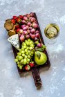 A glass of white wine and snacks on a wooden board — Stock Photo