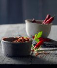 Chilli peppers in grey concrete bowls with parsley and rosemary — Stock Photo