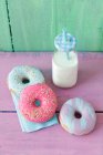 Пончики с цветной сахарной глазурью и бутылкой молока — стоковое фото