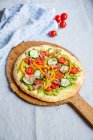 Pizza con aguacate, calabacín, tomates, pimientos y jamón - foto de stock