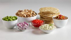 Greek pitta bread surrounded by various ingredients in bowls — Stock Photo