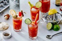 Glasses Bloody Mary cocktails with various vegetable servings — Stock Photo