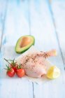 A spiced chicken leg with cherry tomatoes, lemon and avocado — Stock Photo