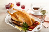 Roasted goose for Christmas dinner filled with apple stuffed and served with apple wedges — Stock Photo