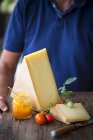 Un homme tenant un plateau de fromage avec des tomates et un pot de confiture — Photo de stock