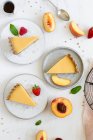 Trozos de tarta en platos con fresas y melocotones - foto de stock