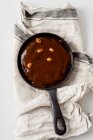 Un brownie cake dans une casserole avec du caramel salé et des cacahuètes rôties — Photo de stock