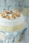 A white festive cake with gold roses and decorative ribbon — Stock Photo