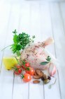 Una pata de pollo especiada con cebolla, aceitunas, almendras, tomates cherry, limón y hierbas - foto de stock
