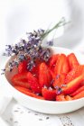 Sliced strawberries with lavender flowers in bowl — Stock Photo