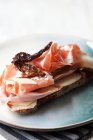 Un sandwich ouvert garni de parmesan, poires, radicchio, tomates séchées et jambon de Parme — Photo de stock