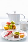 Verschiedene bunte Macarons am Kuchenstand von Teekanne und Tasse — Stockfoto