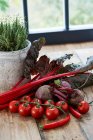 Червоні овочі на дерев'яному столі перед вікном — стокове фото