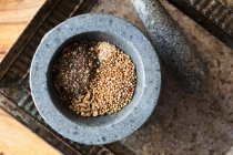 Pepe, zenzero, semi di coriandolo e aglio in un mortaio — Foto stock