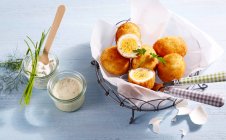 Breaded eggs in parchment paper in a metal basket next to a mustard dip and remoulade — Stock Photo