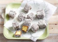 Sponge cake bites with chocolate glaze and grated coconut — Stock Photo