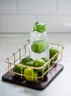Lime and basil lemonade in bottle with limes — Stock Photo