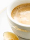 Primer plano de taza de café capuchino caliente con latte arte sobre fondo blanco - foto de stock