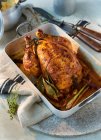 Roast chicken in a roasting tin with linen cloth on stone platter — Stock Photo
