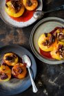 Caramelized plums with pecan nuts on plates with spoons — Stock Photo