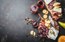 Un piatto di formaggio, carne, cracker, pane, uva e noci con vino rosso — Foto stock