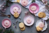 Messy table setting with flowers, pink jelly and cookies — Stock Photo