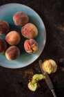 Kleine fränkische Pfirsiche auf Teller und mit Messer auf Tisch halbiert — Stockfoto