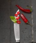 Anillos de chile rojo en la punta de un cuchillo con gotas de agua - foto de stock