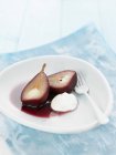 Primo piano di pera in vino rosso con crema — Foto stock
