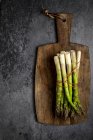 Asparagus with a little red rope on a wooden plank at a black canvas — Stock Photo