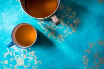 Cilantro y té de jengibre en una taza de metal sobre una superficie azul azur - foto de stock