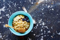 Bowl of classic oatmeal porridge with honey, banana and organic frozen blueberries — Stock Photo