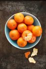 Mandarins, whole and peeled in bowl and on metal surface — Stock Photo