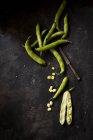 Broad beans on a black surface with an old knife — Stock Photo