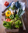 Légumes du marché dans une boîte en bois et sur un carton en bois avec du papier — Photo de stock