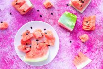 Wassermelonenscheiben auf weißem Teller auf rosa Oberfläche — Stockfoto