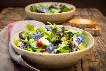 A mixed green salad with avocado, redcurrants and borage flowers — Stock Photo
