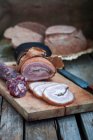 Homemade hard cured sausage and ham on a chopping board — Stock Photo