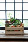 Uma caixa de legumes na frente de uma janela — Fotografia de Stock