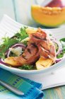 Grilled melon wedges wrapped in ham and served on bed of leaf salad — Stock Photo