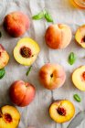Fresh peaches and peach halves on linen tablecloth — Stock Photo