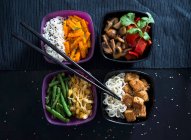 Four bowls with rice, roasted carrots, mushrooms, peppers, beans, mung beans, Mie noodles and tofu (Vegan) — Stock Photo