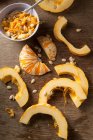 Tranché ? ? citrouilles munchkin et graines de citrouille sur une surface rustique en bois — Photo de stock