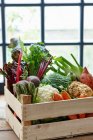 Uma caixa de legumes na frente de uma janela — Fotografia de Stock