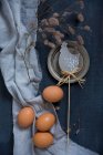 Decorações de Páscoa com ovos de galinha e um galho ao lado de um motivo de frango em um fundo azul — Fotografia de Stock