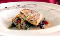Bream fillet on a bed of vegetables with beurre blanc — Stock Photo