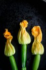Três flores de abobrinha em uma chapa preta — Fotografia de Stock