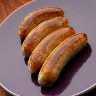 Four English bangers on plate — Stock Photo