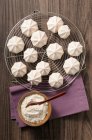 Meringues on cooling rack with small bowl of powdered sugar — Fotografia de Stock